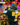 Person wearing a green hoodie with yellow square designs in front of a colorful floral background